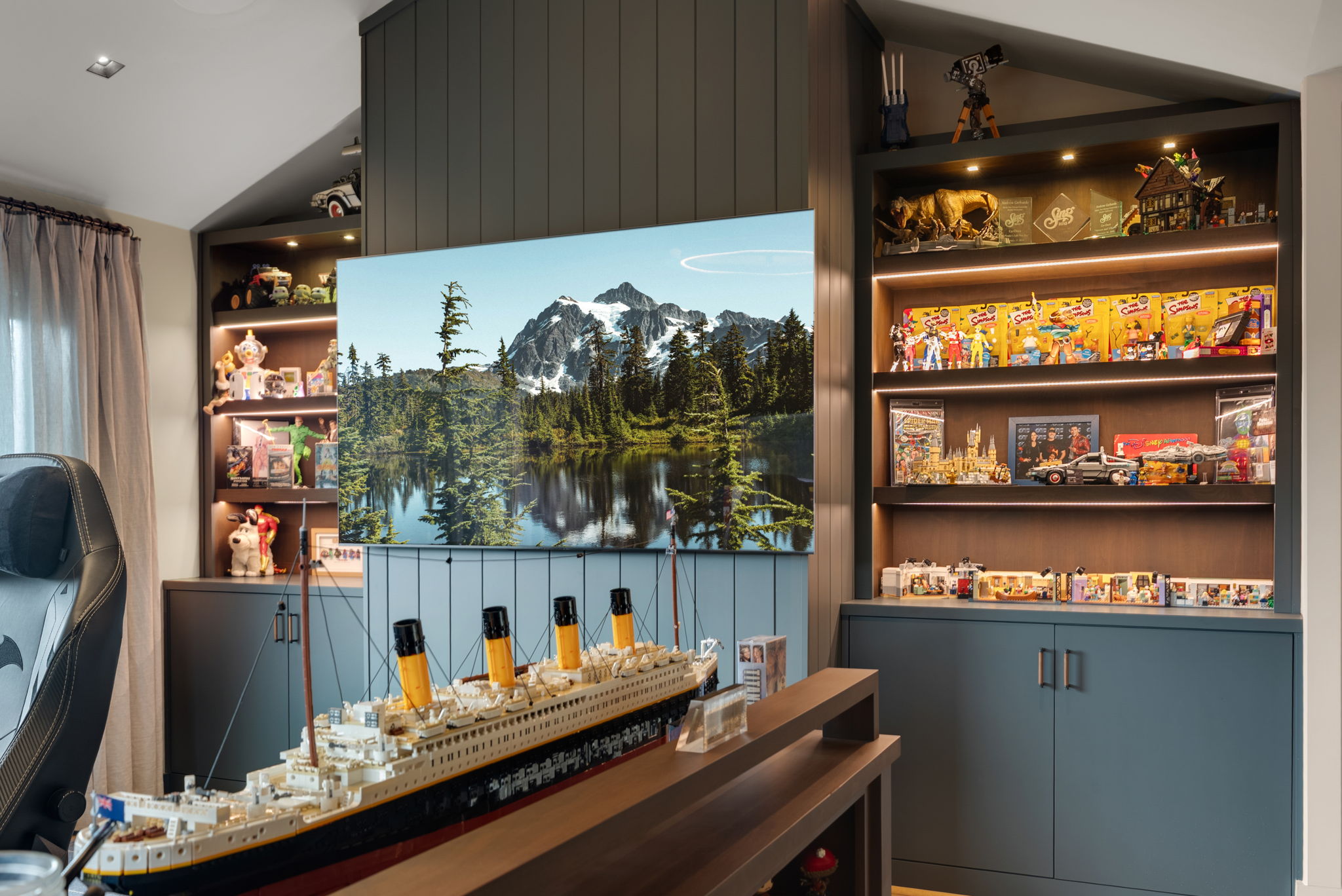 Home office with a large television, illuminated display shelves, and a model ship
