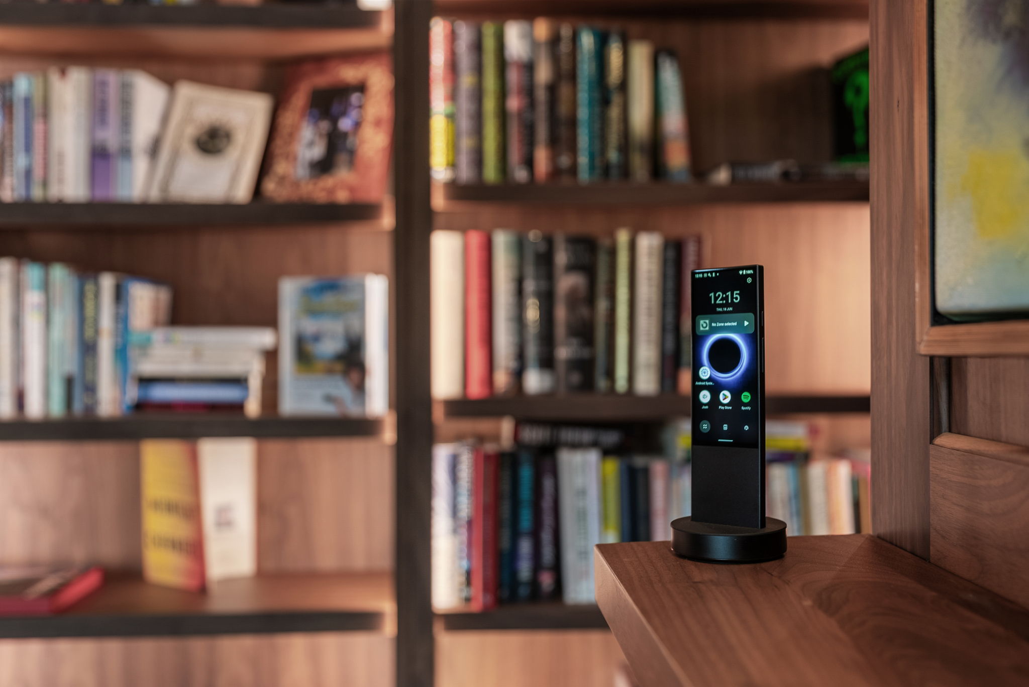 Handheld Control4 remote against a backdrop of library shelves